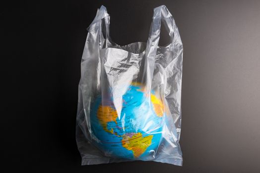 Plastic bag Earth world globe isolated on black background. Saving the planet Earth from plastic bags concept