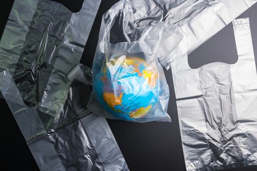 Plastic bag Earth world globe isolated on black background. Saving the planet Earth from plastic bags concept