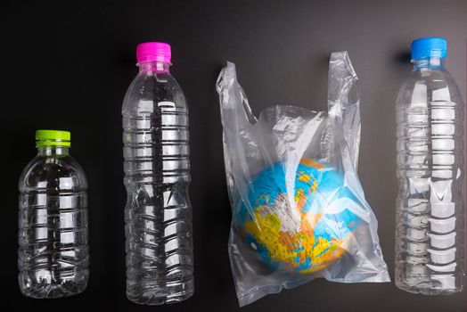 Earth world globe and plastic bottle waste on the black background.Saving the planet Earth from plastic bags concept.Global warming.Plastic waste overflows the world