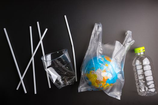 Earth world globe and plastic bottle waste on the black background.Saving the planet Earth from plastic bags concept.Global warming.Plastic waste overflows the world