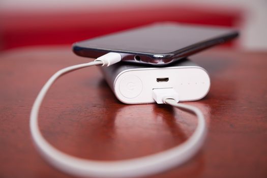 Mobile Phone Charging With Power Bank on wooden table