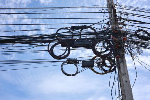 The chaos of cables and wires on the electric power pole Dangers that may arise from the clutter of the power cord With the sky in the background.