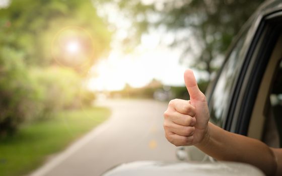 Happy woman raised arms from the car.