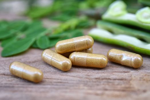 Close up Herbal capsules from moringa herbs on rustic wooden table,background and copy space for using in medical background, healthy eating for good life. Selective focus