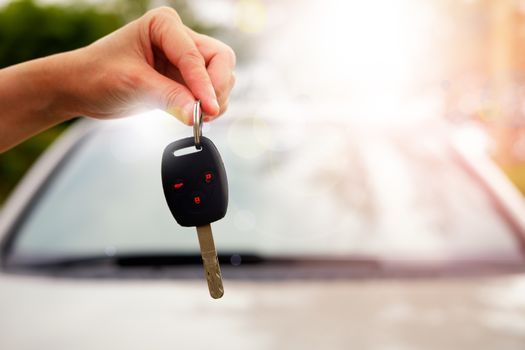 The hand of a woman holding a car key to be submitted to the driver of this car.