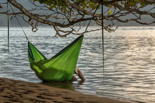 Rear view of romantic couple enjoying sunset in Kauai from hanging swinging hammock