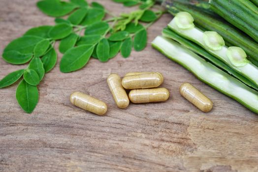 Top view Herbal capsules from moringa herbs on rustic wooden table,background and copy space for using in medical background, healthy eating for good life. Selective focus