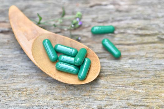 Herbal Medicines / Natural herb capsules Andrographis paniculata in spoon on wooden rustic background and copy space for using in medical background, healthy eating for good life. selective focus