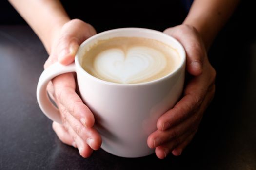 Handle hot cup of coffee, A heart-shaped milk froth, valentine concept.