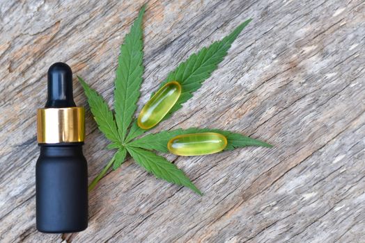 Medical Marijuana, Bottle and Capsule of CBD hemp oil and cannabis leaves on wooden background. Medical concept Researching hemp leaves and hemp oil Using oil as a treatment herb. Selected focus