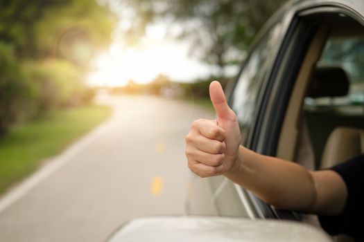 Happy woman raised arms from the car.