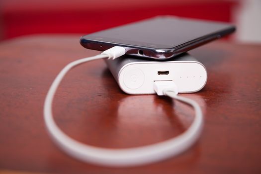 Cell Phone Charging With Power Bank on wooden table