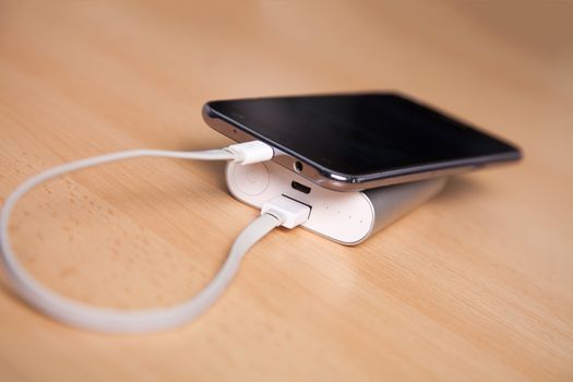 Mobile Phone Charging With Power Bank on wooden table