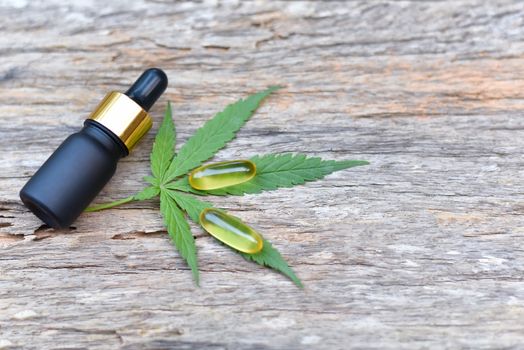 Medical Marijuana, Bottle and Capsule of CBD hemp oil and cannabis leaves on wooden background. Medical concept Researching hemp leaves and hemp oil Using oil as a treatment herb. Selected focus