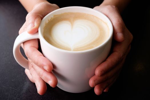 Handle hot cup of coffee, A heart-shaped milk froth, valentine concept.