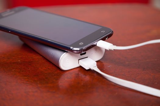 Mobile Phone Charging With Power Bank on wooden table