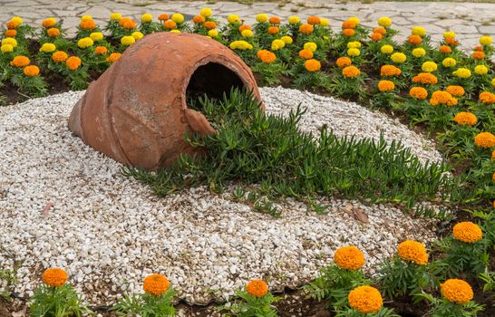 Flowers and gravel surround ceramic urn in ornamental garden