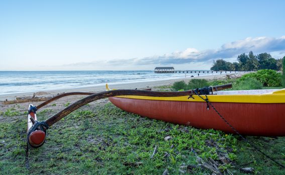 Traditional hawaiian canoe on beach by the pier on Hanalei Bay in Kauai