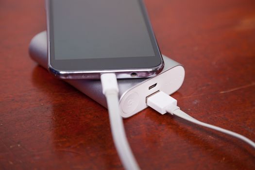 Cell Phone Charging With Power Bank on wooden table
