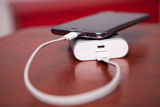 Mobile Phone Charging With Power Bank and USB cord, on wooden table