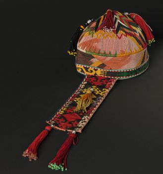 colorful traditional asian skullcap hat with pigtails on a dark background