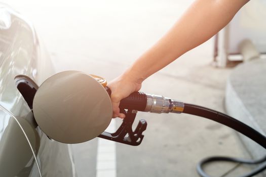 Closeup of man pumping gasoline fuel in car at gas station. Fuel nozzle with hose in hand.