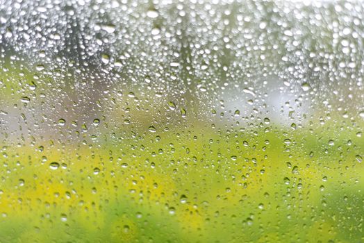 Rain drops on a window with abstract lights or water droplets with abstract blur background as viewed from car window on a rainy day. with selective focus area. Bokeh background concept.