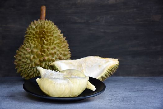 Durian riped. King of Fruits. Durian is a popular tropical fruit in Thailand. Betel of durian on black dish with durian peel on Dark color background. Seasonal fruit concept. Selected focus.