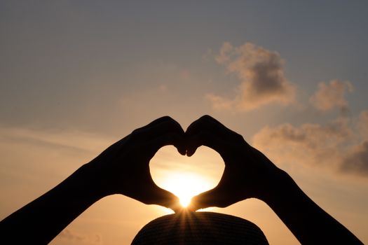 silhouette Hands are making a heart shape to let the sun pass through.