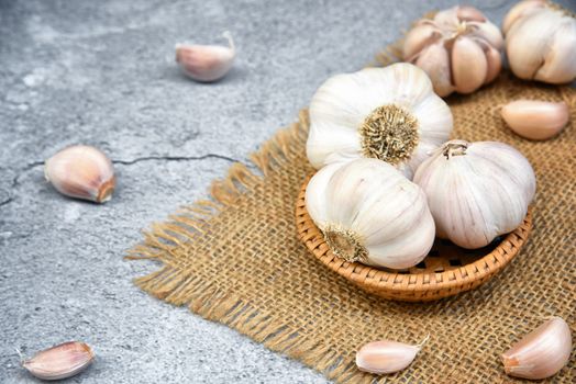 Organic Garlic. Fresh Garlic Cloves and Garlic bulb in wooden basket on dark background with Pile of garlic or spice. Selected focus. Concept of spices for healthy cooking.