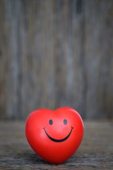 A heart shaped rubber ball rests on old decayed wood. Happy Valentine day concept.