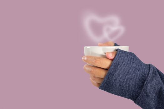 Hand holding a hot coffee cup with heart shaped smoke, love and valentine concept with copy space.