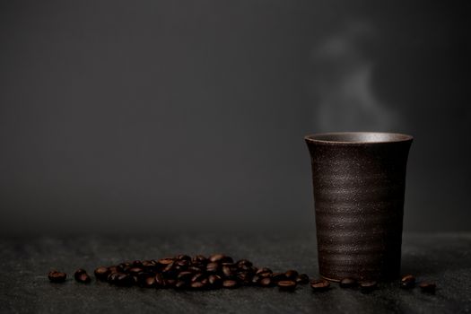 Classic still life - a cup of coffee with smoke and roasted coffee have copy space, dark light picture.