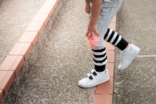 Hand of the boy holding the knee because of injury, can not walk up the stairs.