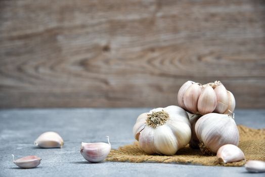 Organic Garlic. Fresh Garlic Cloves and Garlic bulb on jute on dark background with Pile of garlic or spice. Selected focus. Concept of spices for healthy cooking.