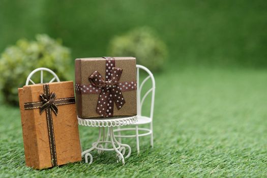 Gift box on white field chair in green garden, with copy space to write.