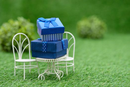 Gift box on white field chair in green garden, with copy space to write.
