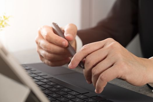 Businessmen are holding pens and sitting thinking something on the computer screen alone.