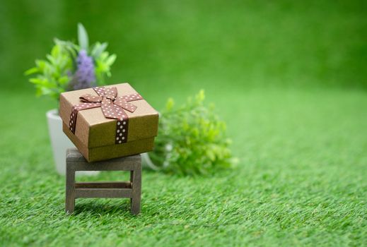 Gift box on brown wooden chair in green garden, with copy space to write.