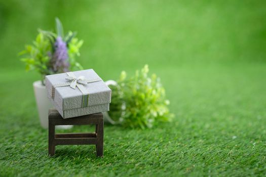 Gift box on brown wooden chair in green garden, with copy space to write.