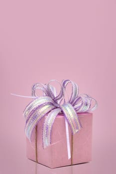Pink gift box with ribbon with copy space on sweet background.