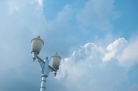 Decorated street lamp on the background of blue sky with white clouds. Copy space.