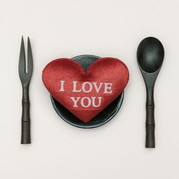 Heart-shaped pillow and mini spoon, folk on pink background, valentine concept.