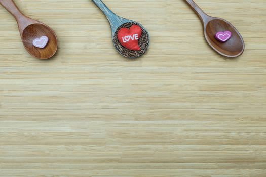 heart-shape and three spoon on wooden background with copy space for write.