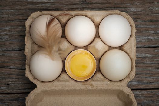 Top view-Yolk and eggs in carton box arranged on a wooden scene, Egg is beneficial to the body, Food concept.