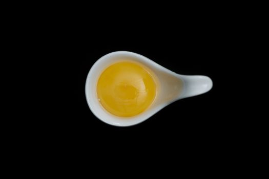 Top view-Yolk Eggs in white ceramic spoon arranged on the black background, Egg is beneficial to the body, Food concept, with copy space.