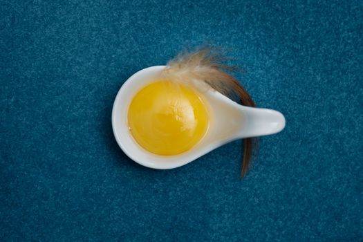 Top view-Yolk Eggs in white ceramic spoon arranged on the blue background, Egg is beneficial to the body, Food concept, with copy space.