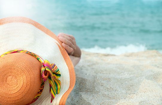 Women wearing hats are sunbathing by the sea.