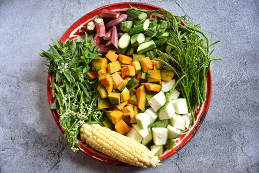 Pumpkin, Zucchini, Thyme, Ocimum basilicum, Chaam, Okra, Sweet Corn in the tray on a dark background. Mixed vegetables ingredients in northeastern food. Thai food menu are bamboo shoot curry.