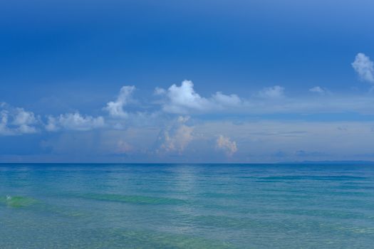 Tropical beach. Blue sky and clear water with white clouds.